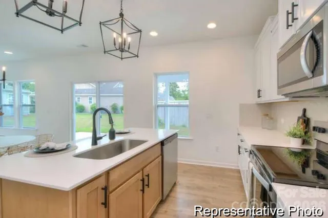 a kitchen with stainless steel appliances granite countertop a sink a stove top oven a counter space and cabinets
