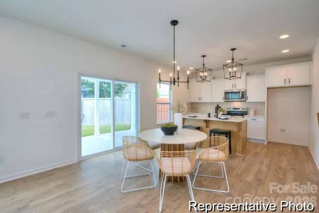 a kitchen with kitchen island a dining table chairs and white cabinets