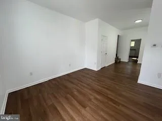 a view of an empty room with wooden floor and closet
