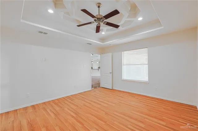a view of empty room with wooden floor and fan