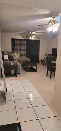 a living room with furniture a flat screen tv and a refrigerator