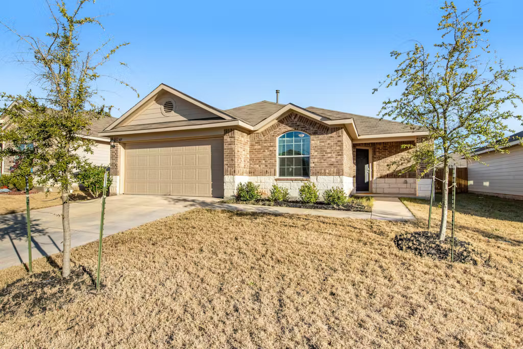 3609 Batson Drive Austin, TX 78725 - Photo 14 of 33 Single story home with brick siding, an attached garage, driveway, and a front lawn