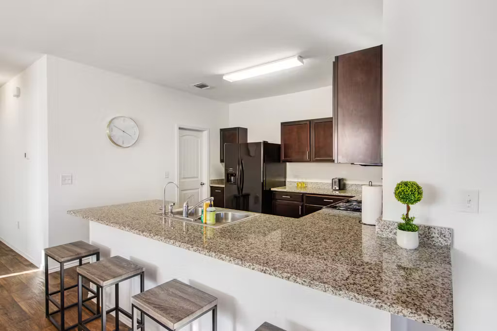 3609 Batson Drive Austin, TX 78725 - Photo 31 of 33 Kitchen featuring a kitchen bar, a peninsula, dark brown cabinets, black fridge with ice dispenser, and dark wood-style floors