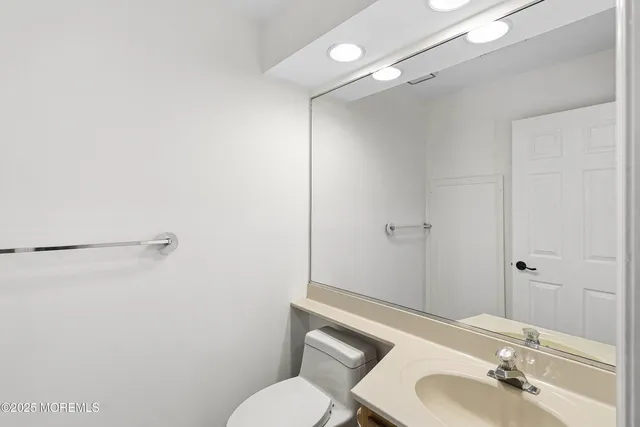 a bathroom with a sink vanity mirror and toilet
