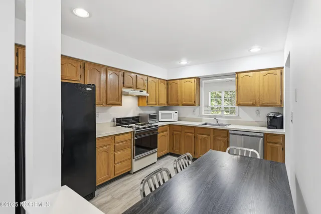 a kitchen with granite countertop a refrigerator stove top oven and sink