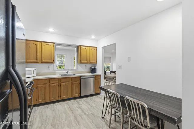 a large white kitchen with wooden floor and stainless steel appliances