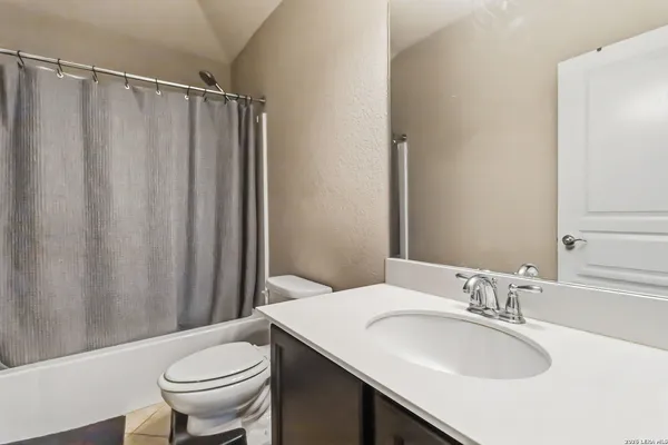 a bathroom with a sink a toilet a mirror and shower curtain