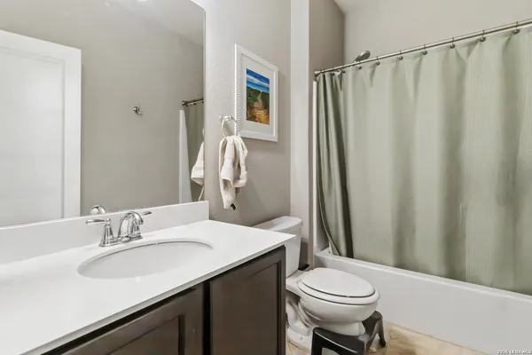 a bathroom with a sink a toilet a mirror and shower curtain