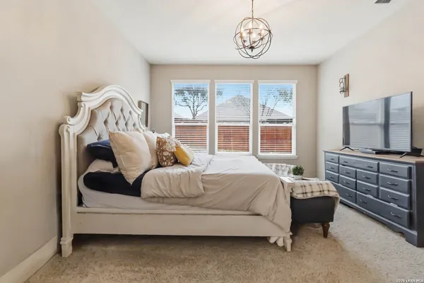 a spacious bedroom with a bed and a flat tv screen on the dresser