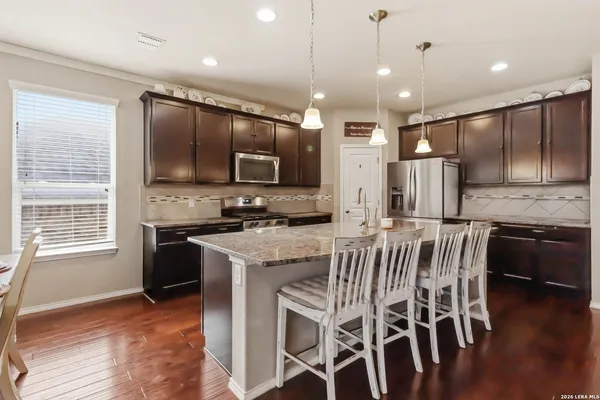 a kitchen with stainless steel appliances kitchen island granite countertop a stove a sink a microwave a island with a dining table and chairs
