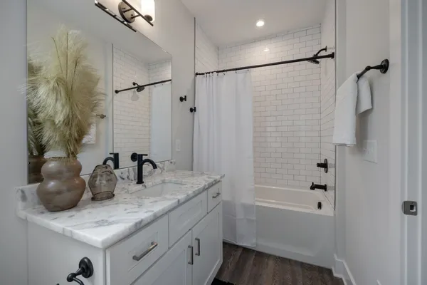 a bathroom with a granite countertop sink a mirror a vanity and shower