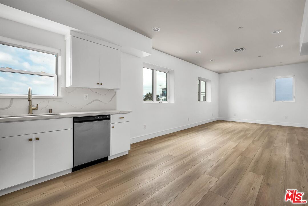 4703 Saturn Street Los Angeles, CA 90019 - Photo 17 of 37 a kitchen with granite countertop white cabinets and white appliances