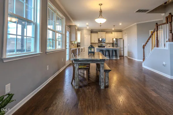a dining room with wooden floor a chandelier a glass table and chairs
