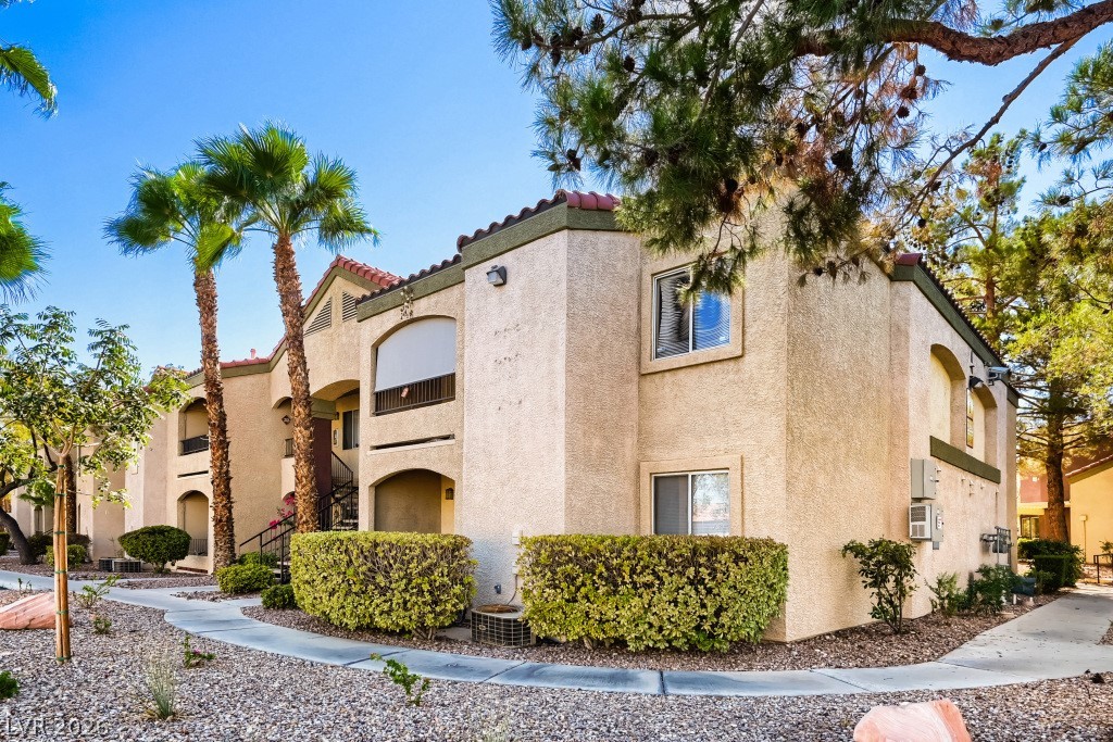7885 West Flamingo Road, Unit 1003 Las Vegas, NV 89147 - Photo 1 of 22 Mature palms and manicured hedges frame this classic southwestern stucco exterior with tile roof accents.