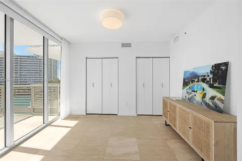 a bedroom with a bed a couch and a flat tv screen next to a window