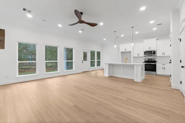 a view of an empty room with wooden floor and a window