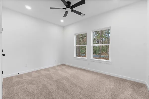 an empty room with windows and fan
