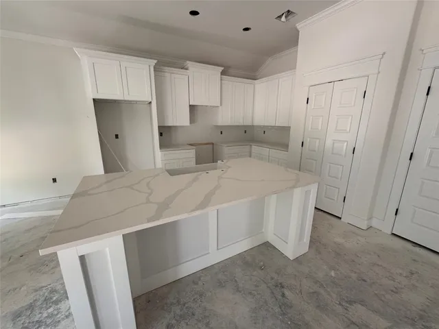 a kitchen with stainless steel appliances kitchen island granite countertop a dining table chairs and white cabinets