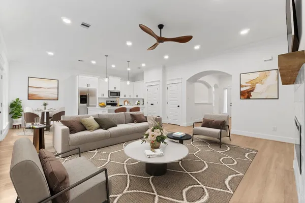 a living room with furniture kitchen view and a wooden floor