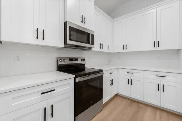 a kitchen with white cabinets and black appliances
