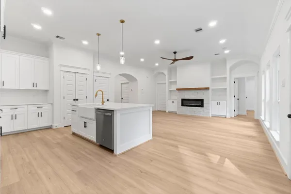 a large white kitchen with a sink a fireplace and a refrigerator