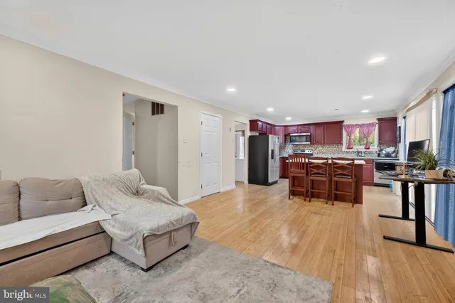a living room with furniture and kitchen view with wooden floor