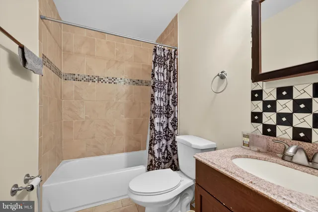 a bathroom with a granite countertop bathtub sink vanity mirror and toilet