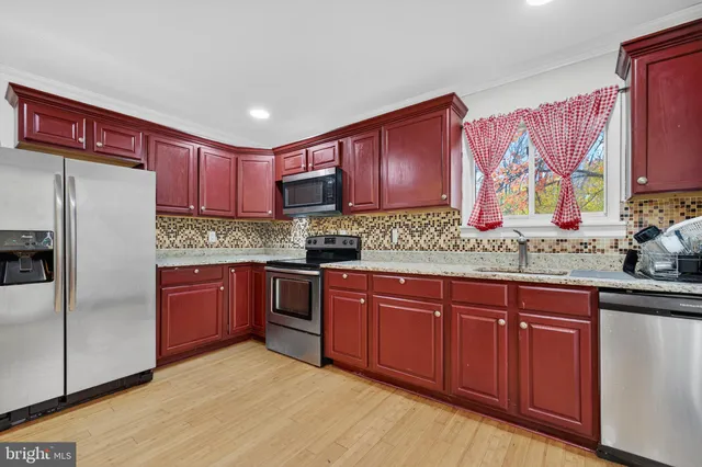 a kitchen with stainless steel appliances granite countertop a refrigerator sink and wooden cabinets