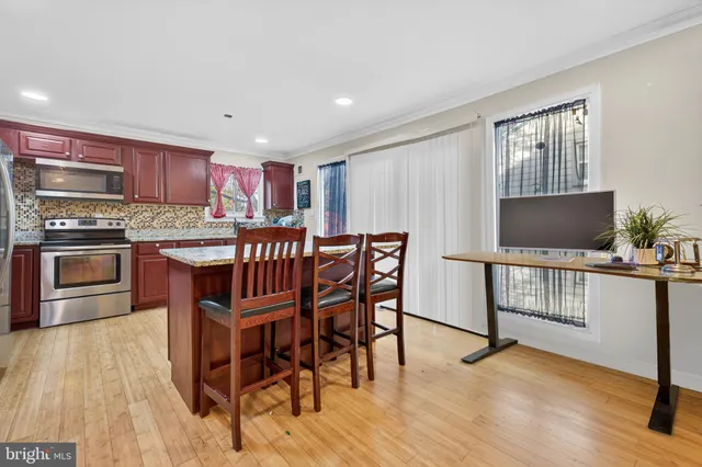 a open kitchen with stainless steel appliances granite countertop a stove top oven a sink dishwasher a dining table and chairs with wooden floor