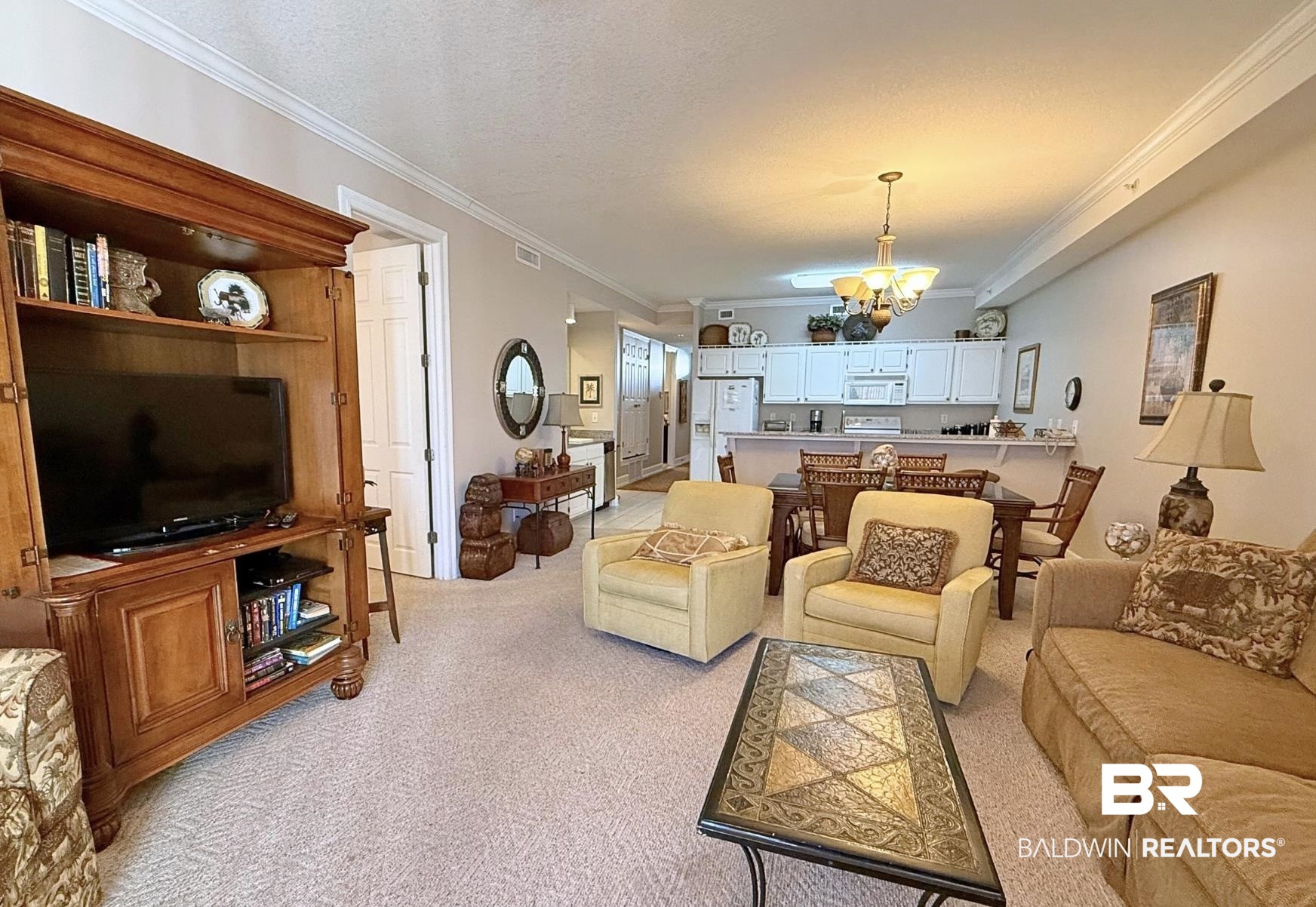 27284 Gulf Road, Unit 212 Orange Beach, AL 36561 - Photo 4 of 35 Living area with a textured ceiling, light colored carpet, hanging lights, and crown molding