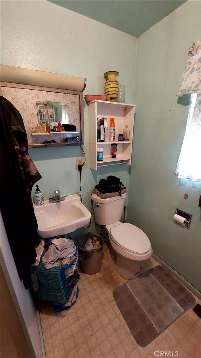 1547 Blackburn Avenue Corning, CA 96021 - Photo 45 of 51 a white toilet sitting next to a bathroom sink and vanity