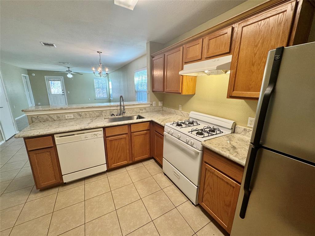 7812 Duber Lane Austin, TX 78747 - Photo 7 of 15 a white kitchen with a sink a stove top oven and cabinetry