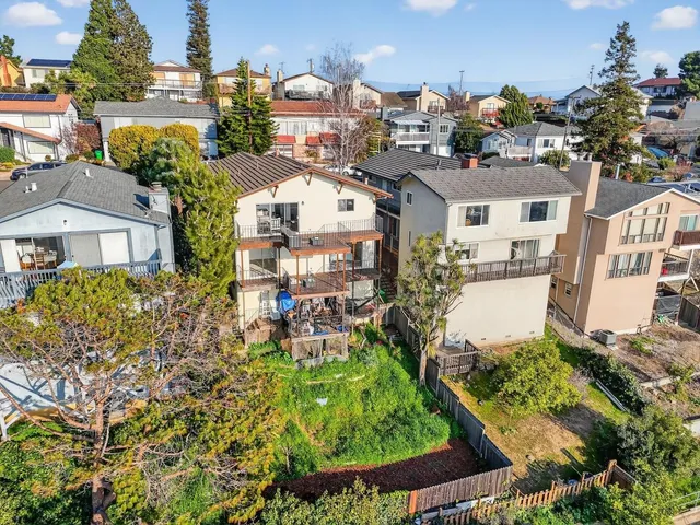 an aerial view of residential houses with outdoor space and trees
