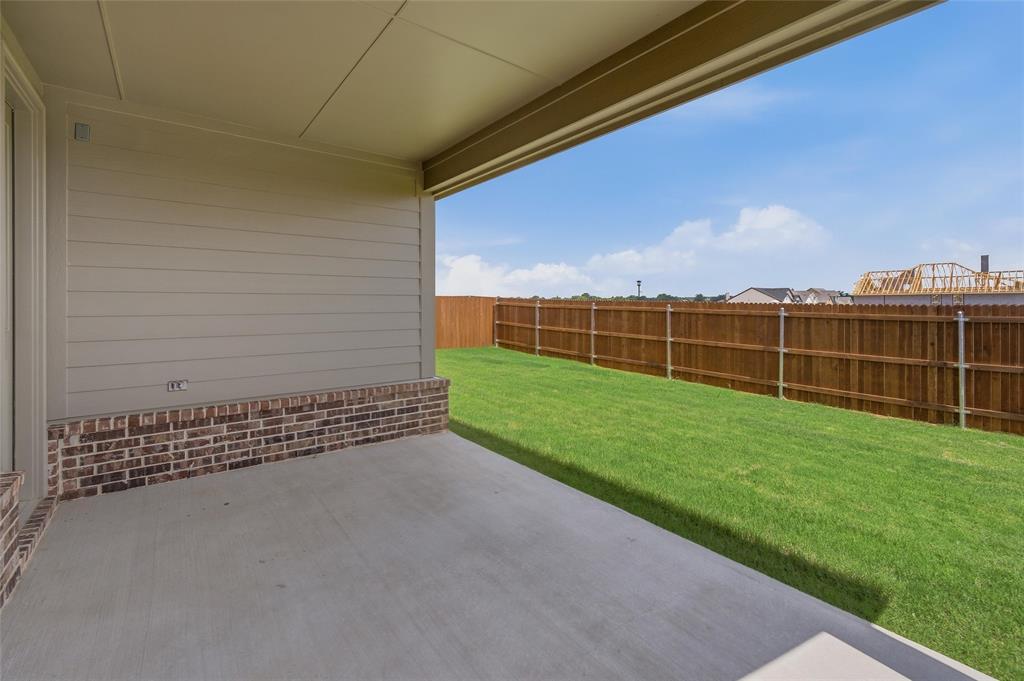 1217 Colca Drive Springtown, TX 76082 - Photo 21 of 25 Covered concrete patio with a painted ceiling, brick and siding exterior, expansive green lawn, and a perimeter wood fence