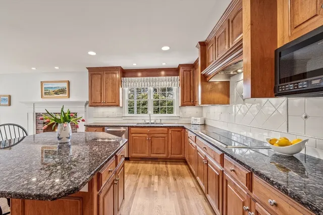 a kitchen with stainless steel appliances granite countertop a sink a stove and a wooden cabinets
