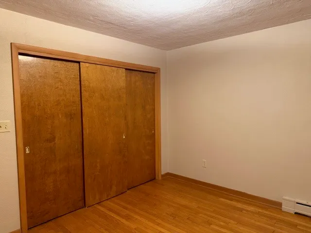 an empty room with wooden floor and sliding window