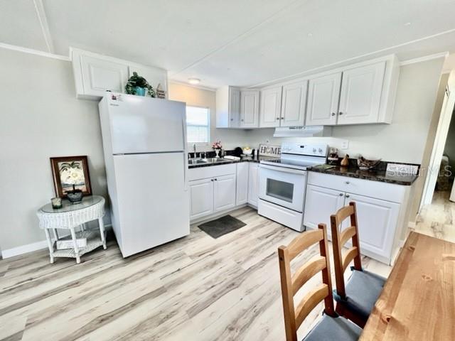 10826 Tioga Drive Port Richey, FL 34668 - Photo 13 of 59 a kitchen with stainless steel appliances granite countertop a refrigerator a stove a sink dishwasher and white cabinets with wooden floor