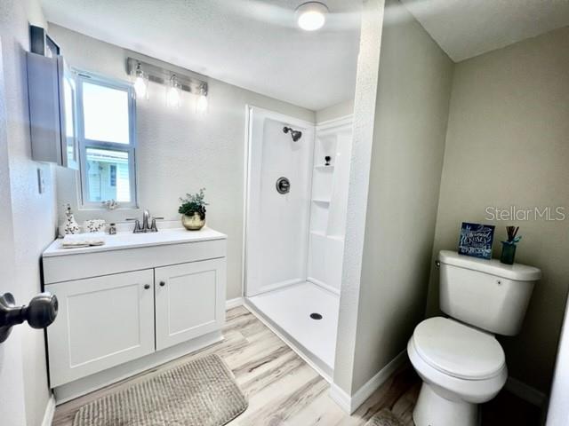 10826 Tioga Drive Port Richey, FL 34668 - Photo 36 of 59 a bathroom with a granite countertop toilet a sink and a mirror