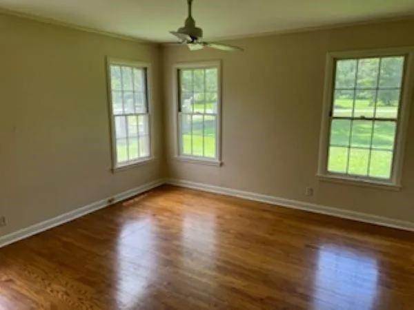 a view of an empty room with wooden floor and a window