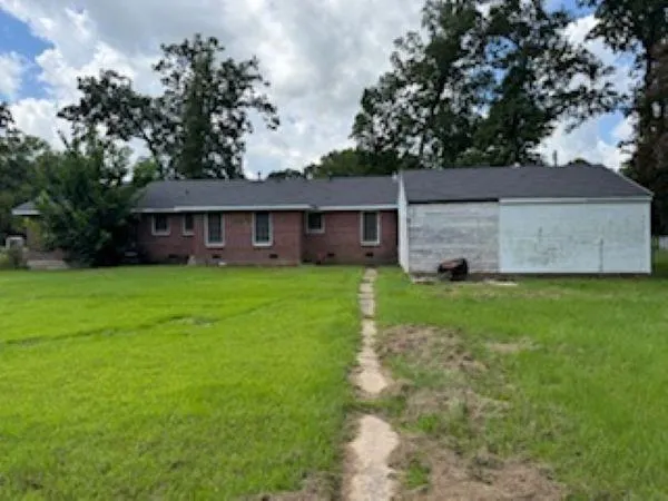a view of a house next to a big yard and large trees