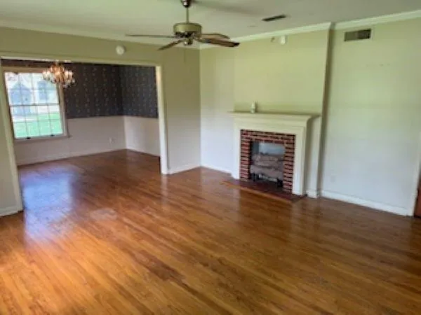 an empty room with wooden floor fireplace and windows