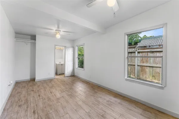 a view of an empty room with a window and wooden floor