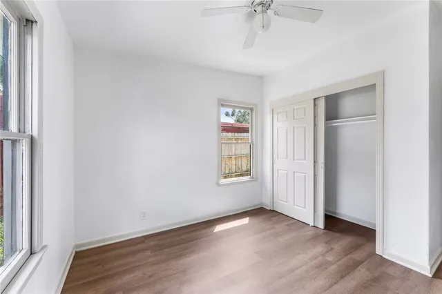 an empty room with wooden floor fan and windows