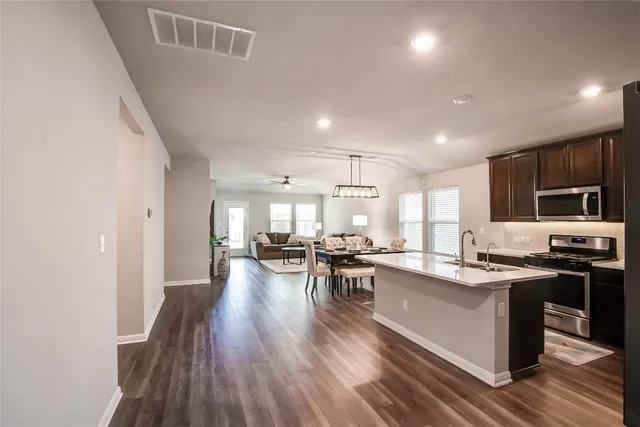 a kitchen with stainless steel appliances kitchen island granite countertop a lot of counter space and a refrigerator