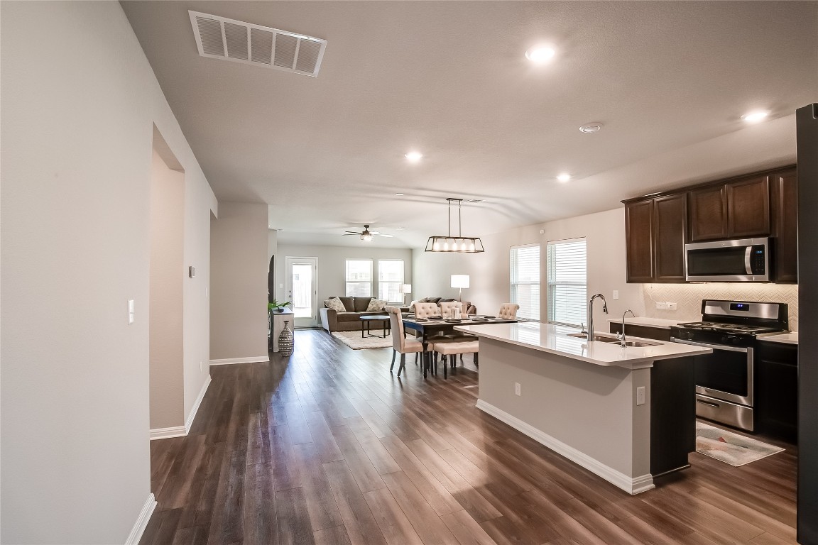 403 Grapefruit Road Hutto, TX 78634 - Photo 5 of 30 a kitchen with stainless steel appliances kitchen island granite countertop a lot of counter space and a refrigerator