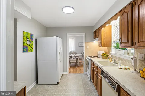 a kitchen with a refrigerator a stove a sink a dining table and chairs