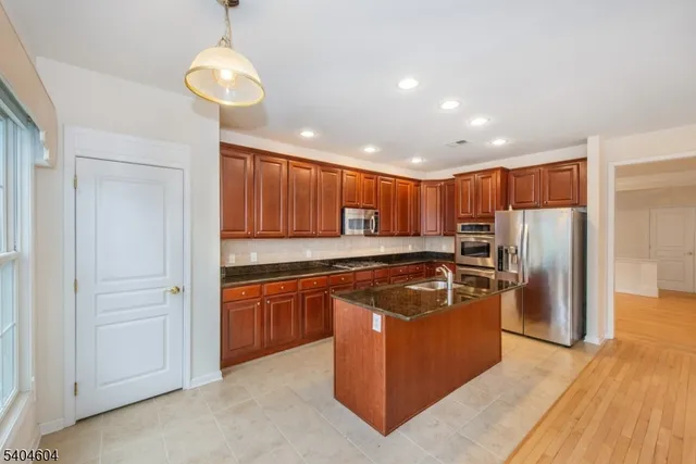a kitchen with stainless steel appliances granite countertop a refrigerator a sink and a stove