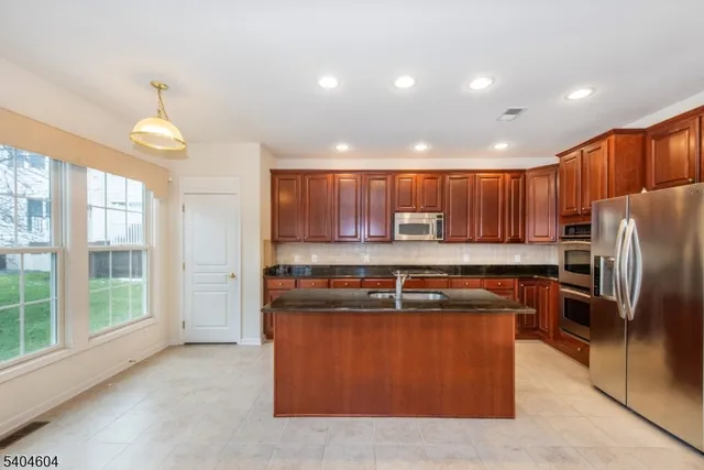 a kitchen with stainless steel appliances granite countertop a stove top oven a refrigerator a sink and dishwasher