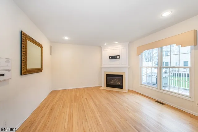 a view of empty room with wooden floor and fireplace