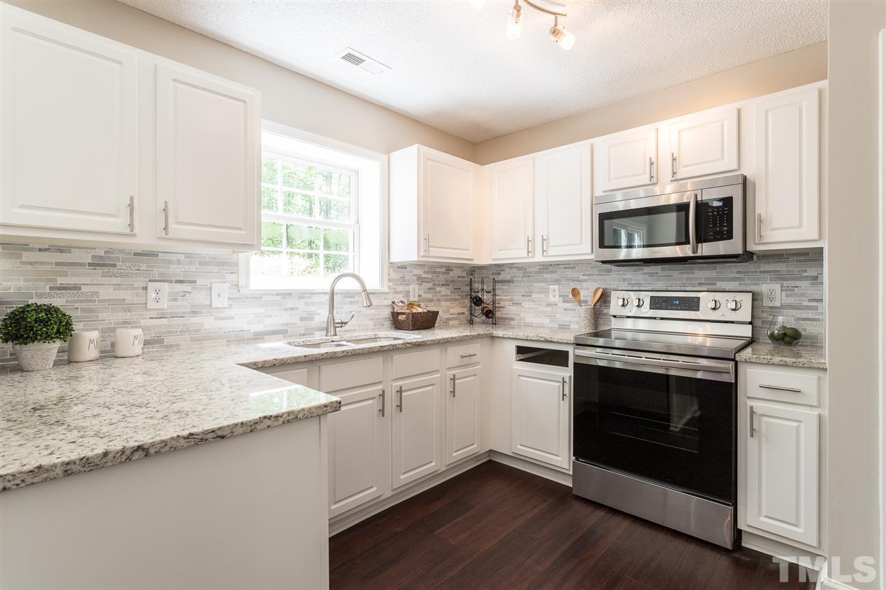 4628 Drewbridge Way Raleigh, NC 27604 - Photo 7 of 21 a kitchen with granite countertop a sink cabinets and stainless steel appliances